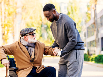 caregiver helping senior man to stand